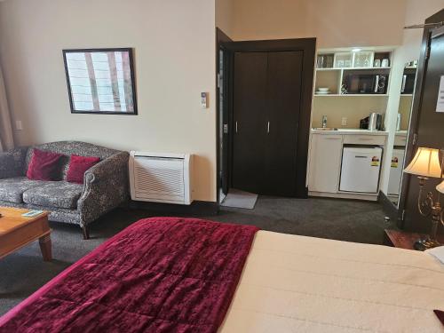 a bedroom with a bed and a living room with a couch at Gateway Motor Inn in Masterton
