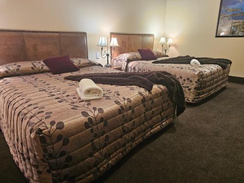 a hotel room with two beds with a towel on them at Gateway Motor Inn in Masterton