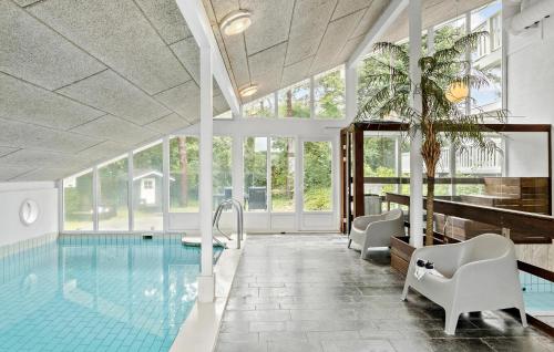 an indoor pool with chairs and a table and a swimming pool at Stunning Home In Roslev With Sauna in Glyngøre