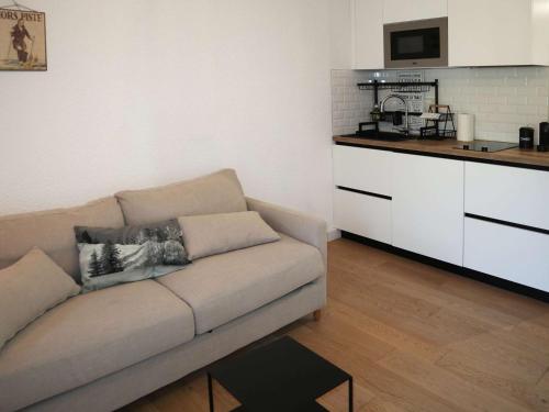 un salon avec un canapé et une cuisine dans l'établissement Coquet studio skis aux pieds, plein centre, balcon sud - FR-1-322-638, aux Orres