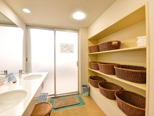 a bathroom with a sink and baskets on the shelves at Yamamoto Ryokan in Kyoto