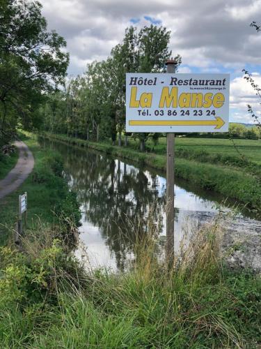 a sign for a la masyasy sign next to a canal at Hôtel Restaurant La Manse in Dornecy
