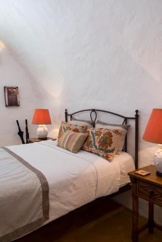 a bedroom with a bed with pillows and two lamps at Hacienda Santa Cruz Merida in Mérida