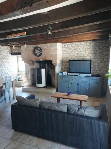 un salon avec un canapé et une télévision dans l'établissement Maison chez l'habitant à 35 minutes du Futuroscope, à Sossais