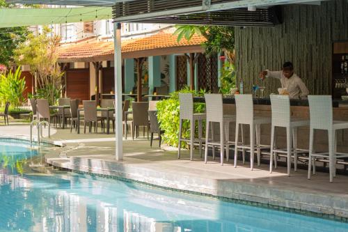 a man sitting at a bar next to a swimming pool at Prime Plaza Hotel Sanur – Bali in Sanur