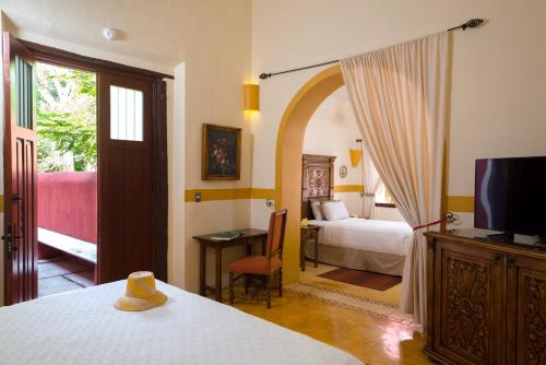 a bedroom with a bed and a tv and a room with a bed at Hacienda Santa Cruz Merida in Mérida