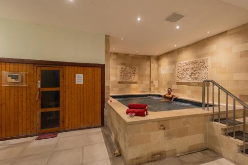 a man sitting in a pool in a house at Prime Plaza Hotel Sanur – Bali in Sanur