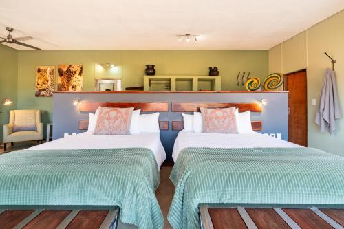 two beds in a room with green walls at Okonjima Plains Camp in Otjiwarongo