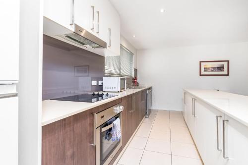 a kitchen with wooden cabinets and white appliances at Modern 2BR 2BA Apartment Close to City and ANU - Hosted by Canstay in Canberra