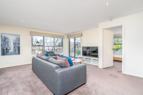 a living room with a gray couch and a tv at Modern 2BR 2BA Apartment Close to City and ANU - Hosted by Canstay in Canberra