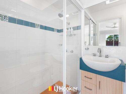 a white bathroom with a sink and a shower at Riverview Apartment 2.4 in Iluka