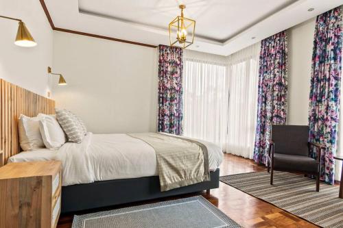 a bedroom with a bed and a chair and curtains at Kirimara Woodlands, Nanyuki in Nanyuki