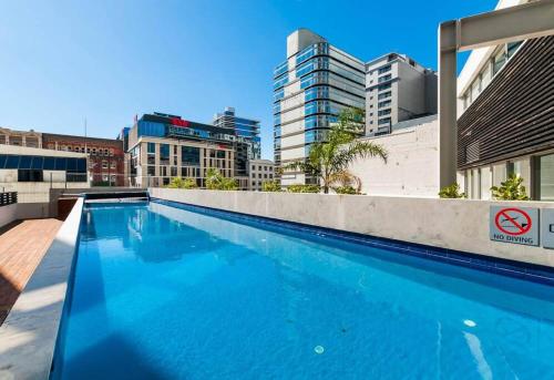a large blue swimming pool with buildings in the background at Character Apartment in Central Downtown Auckland in Auckland