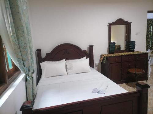 a bedroom with a bed and a dresser and a mirror at The Kingston Court in Kandy