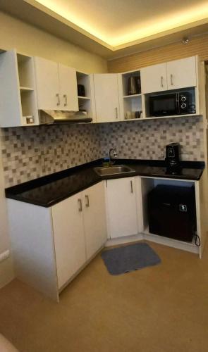 a kitchen with white cabinets and a black counter top at Avida Davao Condos, downtown CM Recto Avenue, Davao City in Davao City
