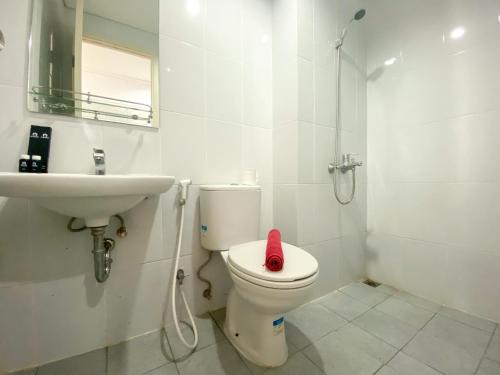 a white bathroom with a toilet and a sink at Luxury and Minimalist Studio at Patraland Urbano Apartment By Travelio in Bekasi