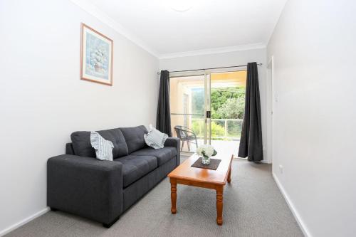 a living room with a couch and a table at Opposite Bennetts Beach in Hawks Nest