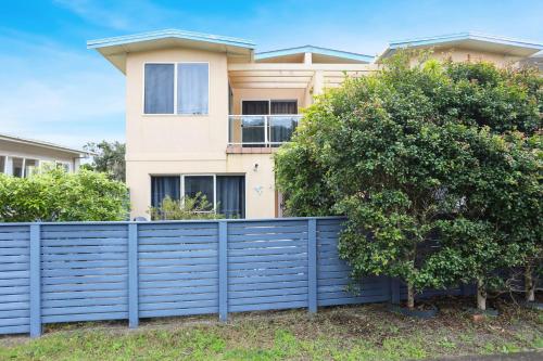 a house with a blue fence in front of it at Opposite Bennetts Beach in Hawks Nest