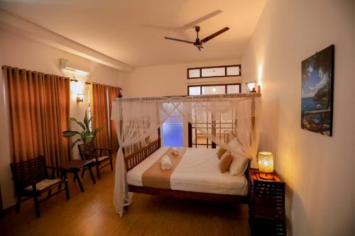 a bedroom with a bed with a canopy at Nibbana Mirissa Hotel in Mirissa