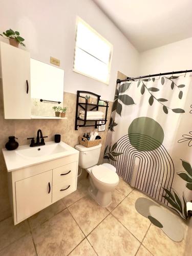 a bathroom with a toilet and a shower curtain at La Casandra Beach House in Isabela