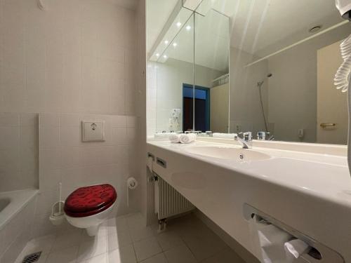 a bathroom with a sink and a toilet and a mirror at Hotel Rosenstadt & Malxestube Restaurant in Noßdorf