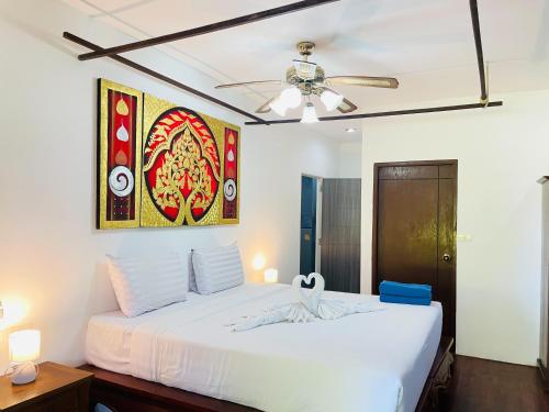 a bedroom with a white bed and a ceiling fan at Boomerang Village Resort Kata in Kata Beach