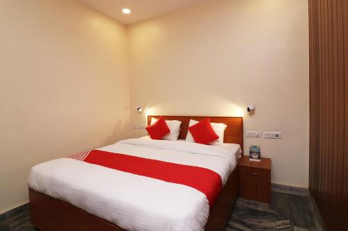 a hotel room with a large bed with red pillows at Hotel O Meerut International in Meerut