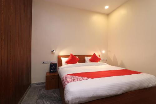 a bedroom with a large bed with red pillows at Hotel O Meerut International in Meerut