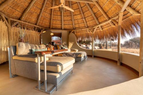 a living room with a thatched roof at Okonjima Luxury Bush Camp in Otjiwarongo