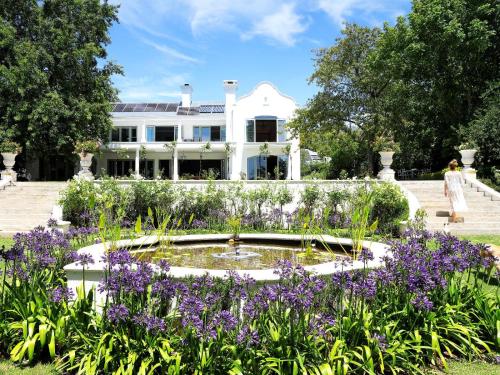 a garden with purple flowers in front of a white house at Constantia Klein in Cape Town