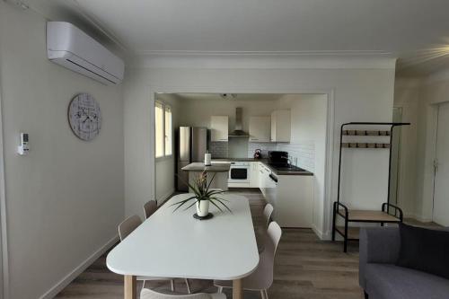 Il comprend un salon blanc avec une table et une cuisine. dans l'établissement BEL appartement T5 NEUF avec 4 chambres, à Tarbes