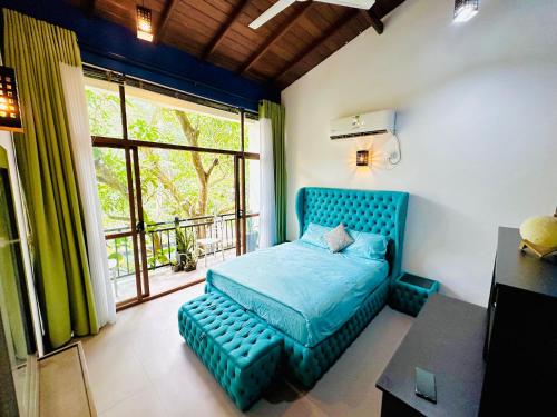 a bedroom with a blue bed and a window at Gampaha Heritage in Gampaha