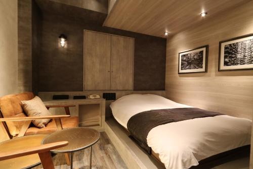 a bedroom with a bed and a table and a chair at HOTEL Us Bentenbashi Adult only in Niigata