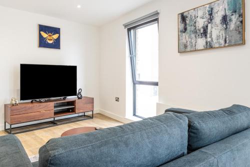 a living room with a blue couch and a flat screen tv at Bayut1 in Manchester
