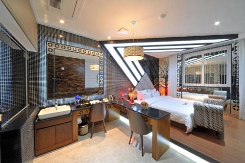 a bedroom with a bed and a desk and a sink at Mokpo Myeongpum Hotel in Mokpo