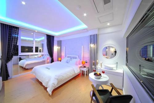 a bedroom with a large white bed and a television at Mokpo Myeongpum Hotel in Mokpo