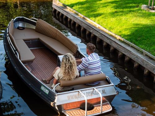 two people sitting in a small boat in the water at De Sloothaak in Giethoorn