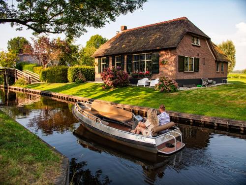 a man and a dog in a boat in front of a house at De Sloothaak in Giethoorn