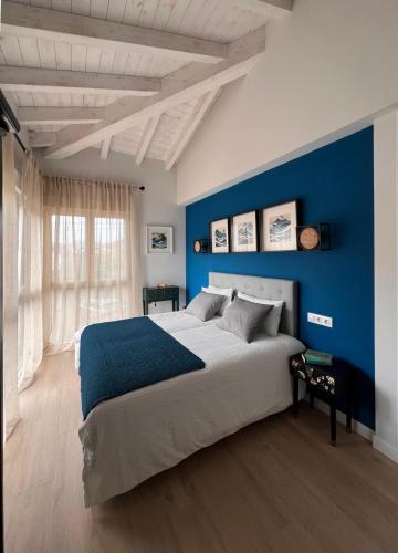 a bedroom with a large bed with a blue wall at Azul Andrin in Andrín