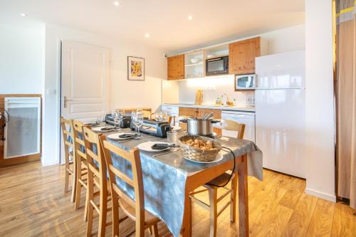 une cuisine avec une table avec des chaises et un réfrigérateur dans l'établissement Le Machu - Appt 3 vue montagne, à Chamrousse