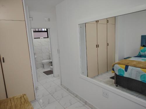 a mirror in a room with a bed and a bathroom at 304 Amazibu- Luxury On the Beach in Amanzimtoti
