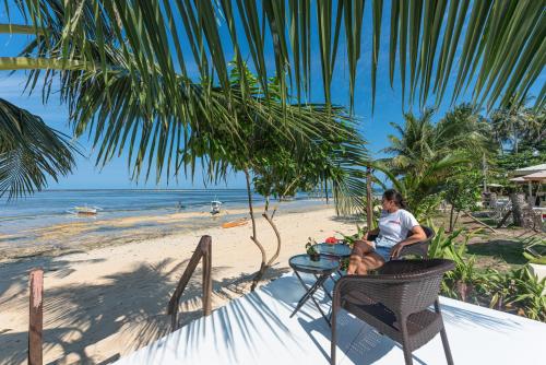 a man sitting at a table on the beach at YAMA APARTMENTS - Private Beachfront in General Luna