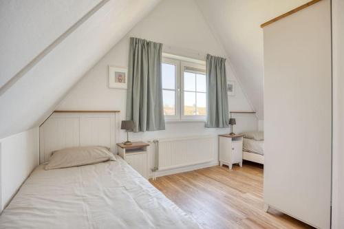 a white bedroom with a bed and a window at Beachvilla it Langezand - Villa aan het vaarwater en vlakbij strand in Makkum