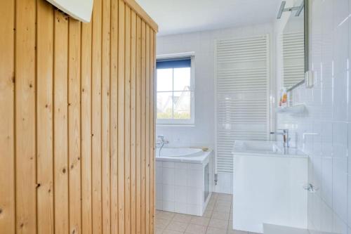 a bathroom with a white tub and a sink at Beachvilla it Langezand - Villa aan het vaarwater en vlakbij strand in Makkum