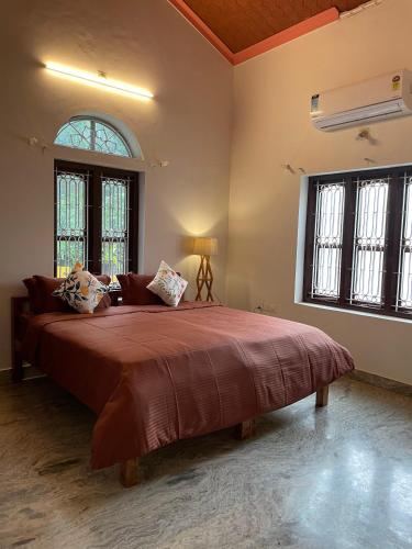 a bedroom with a large bed in a room with windows at Kulture KonnectT in Varkala