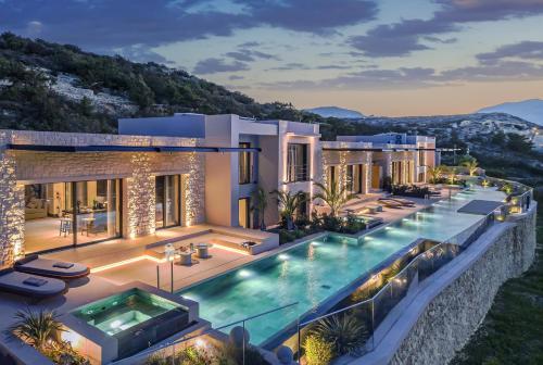 a villa with a swimming pool at night at Omega Residences in Karpathos
