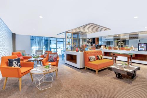 an office lobby with orange chairs and tables at INNSiDE by Meliá Yogyakarta in Yogyakarta
