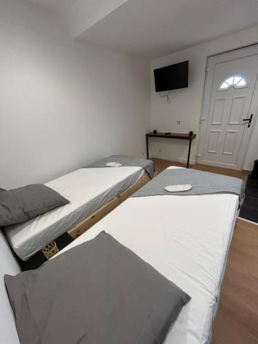 Cette chambre comprend 3 lits et une télévision à écran plat. dans l'établissement Maison BR, à Villeneuve-le-Roi