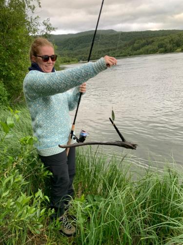 a woman is holding up a fishing pole at Mitt paradis in Bardufoss