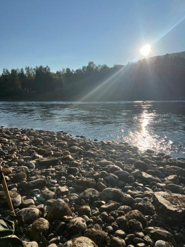 a rocky shore of a river with the sun in the background at Mitt paradis in Bardufoss